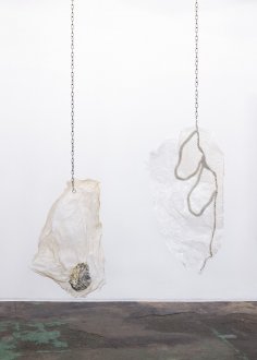 Andreia Santana, <i>Saliva Makes Corals Dance in Fountains</i>, and <i>Body Armor (For Zachary)</i>.
<br>
<br>
Andreia Santana's sculptures "Saliva Makes Corals Dance in Fountains" (left) and "Body Armor (For Zachary)" on the right are fashioned from liquid fish glue, which the artist spread out on the gallery's floor to dry. Though they were produced "impromptu", it is their sculptural qualities - their contours and the distortion of the now-dried puddles - which make them interesting as sculptures. The inlaid chains, from which they are suspended, speak to the general interests of the artist who often juxtaposes fragile with industrial materials. The stainless steel scaffoldings of her series of "Roof of Mouths" (see further installation views), for example, hold delicate glass plates molded from found organic or inorganic relics, including debris and wildlife.